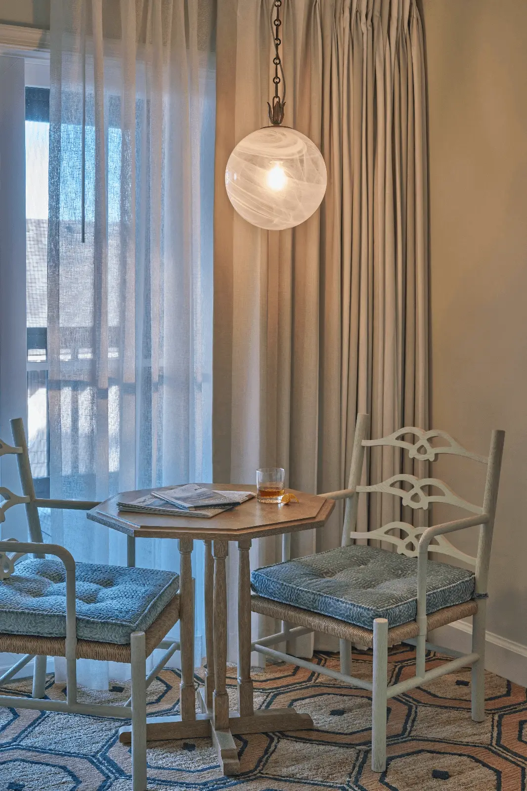 Beautiful corner of the room with a table and two chairs, bathed in the warm glow of a hanging lamp.