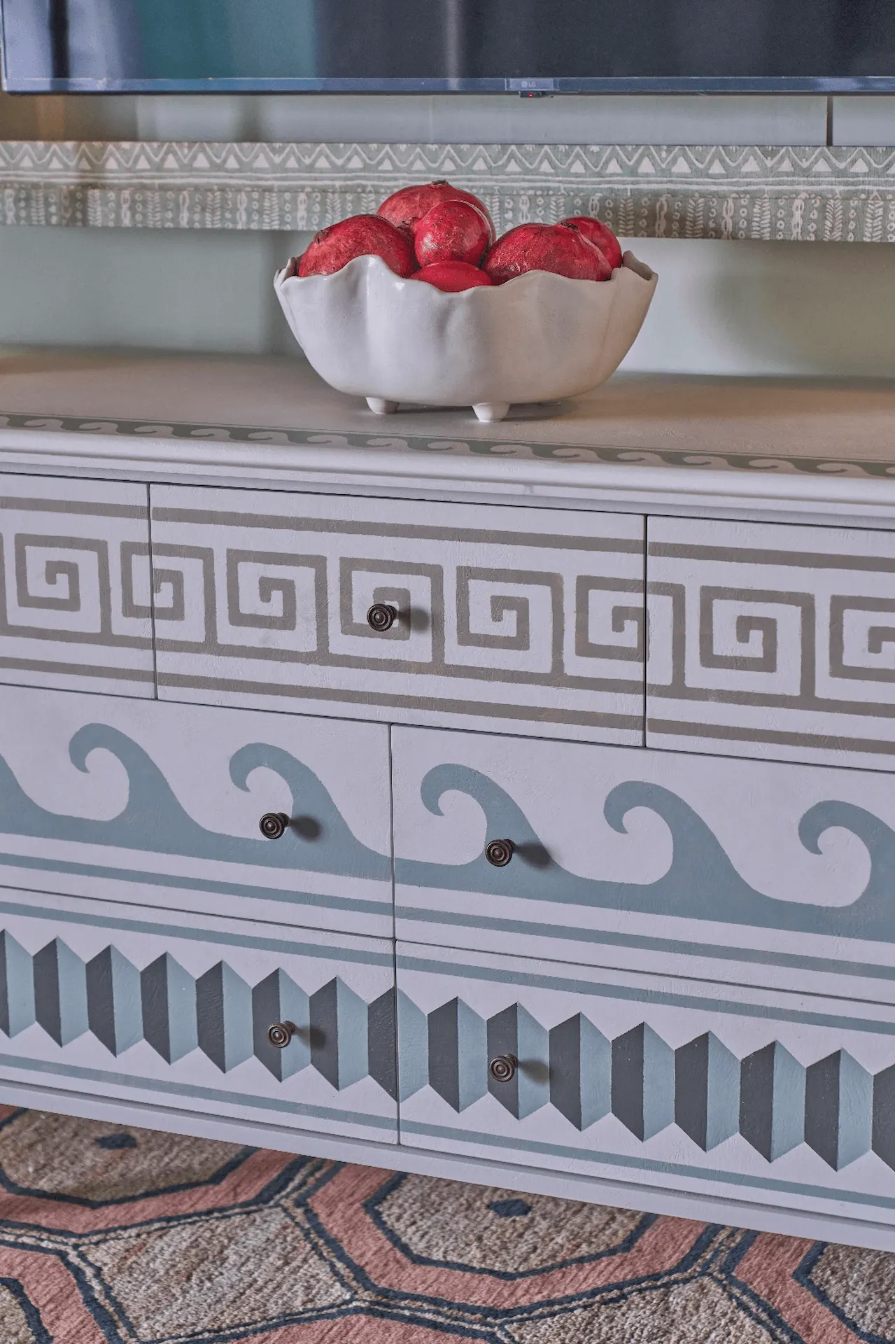 Cabinet with Greek-inspired design and an elegant bowl of red pomegranates.